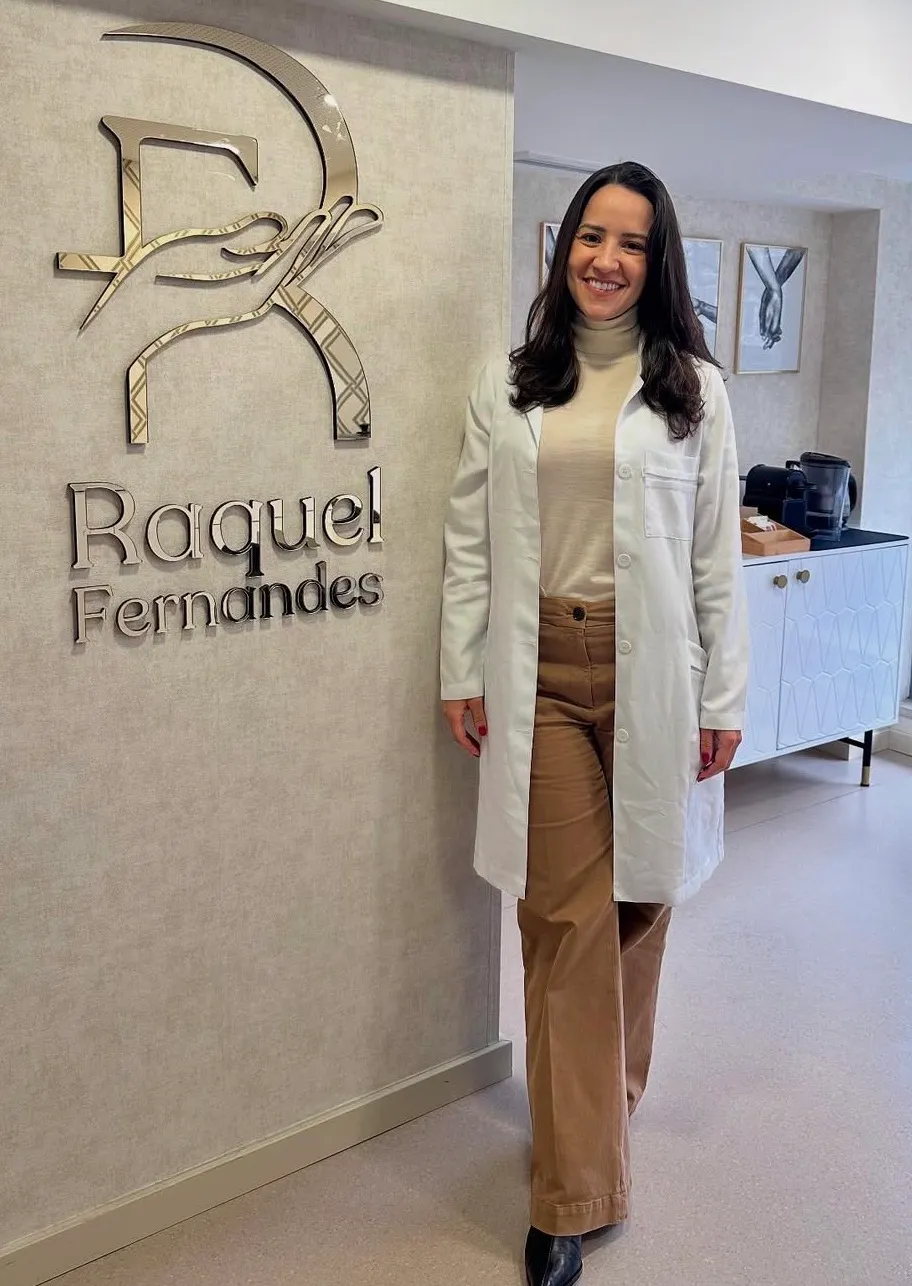 Raquel Fernandes no consultório, ao lado do logótipo na parede